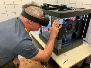 Man with simulation lens operates a 3Dprinter